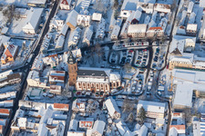 Aerial view of Wintry snowy Christmassy market event grounds and sale huts and booths on market place around tha church Sankt Georgskirche in Kandel in the state Rhineland-Palatinate, Germany