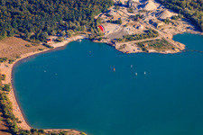 Sailboats, sunbathers and bathers on and in the blue Epplesee lake, flown over by a paraglider. in the district Silberstreifen in Rheinstetten in the state Baden-Wuerttemberg, Germany