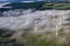 Weather-induced wind energy installations embedded in a fog layer on a field in the district Fuerstenau in Hoexter in the state North Rhine-Westphalia