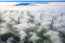 Oblique view of Rotors of wind farm Fürstenau protrude from low clouds in the district Fürstenau in Höxter in the state North Rhine-Westphalia, Germany