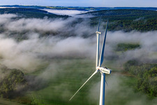 Rotors of wind farm Fürstenau protrude from low clouds in the district Fürstenau in Höxter in the state North Rhine-Westphalia, Germany out of the air