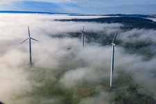 Rotors of wind farm Fürstenau protrude from low clouds in the district Fürstenau in Höxter in the state North Rhine-Westphalia, Germany seen from above